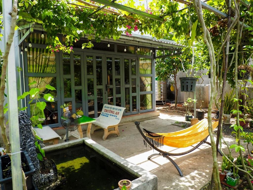 La cour de Coco Happy Farm, un hamac jaune et un bassin sous une tonnelle de bougainvilliers