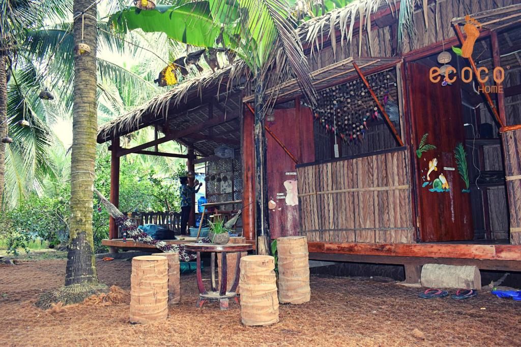 Une cabane de bois et de feuilles de palmier d'Ecoco, des tabourets en tronc de cocotier devant la porte