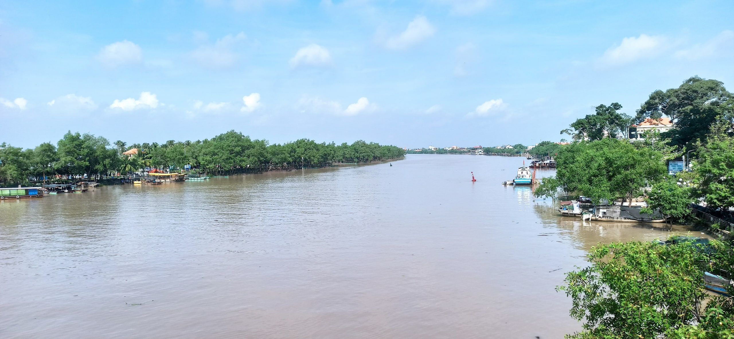 La rivière de Bến Tre, large et brune, entre deux rives boisées