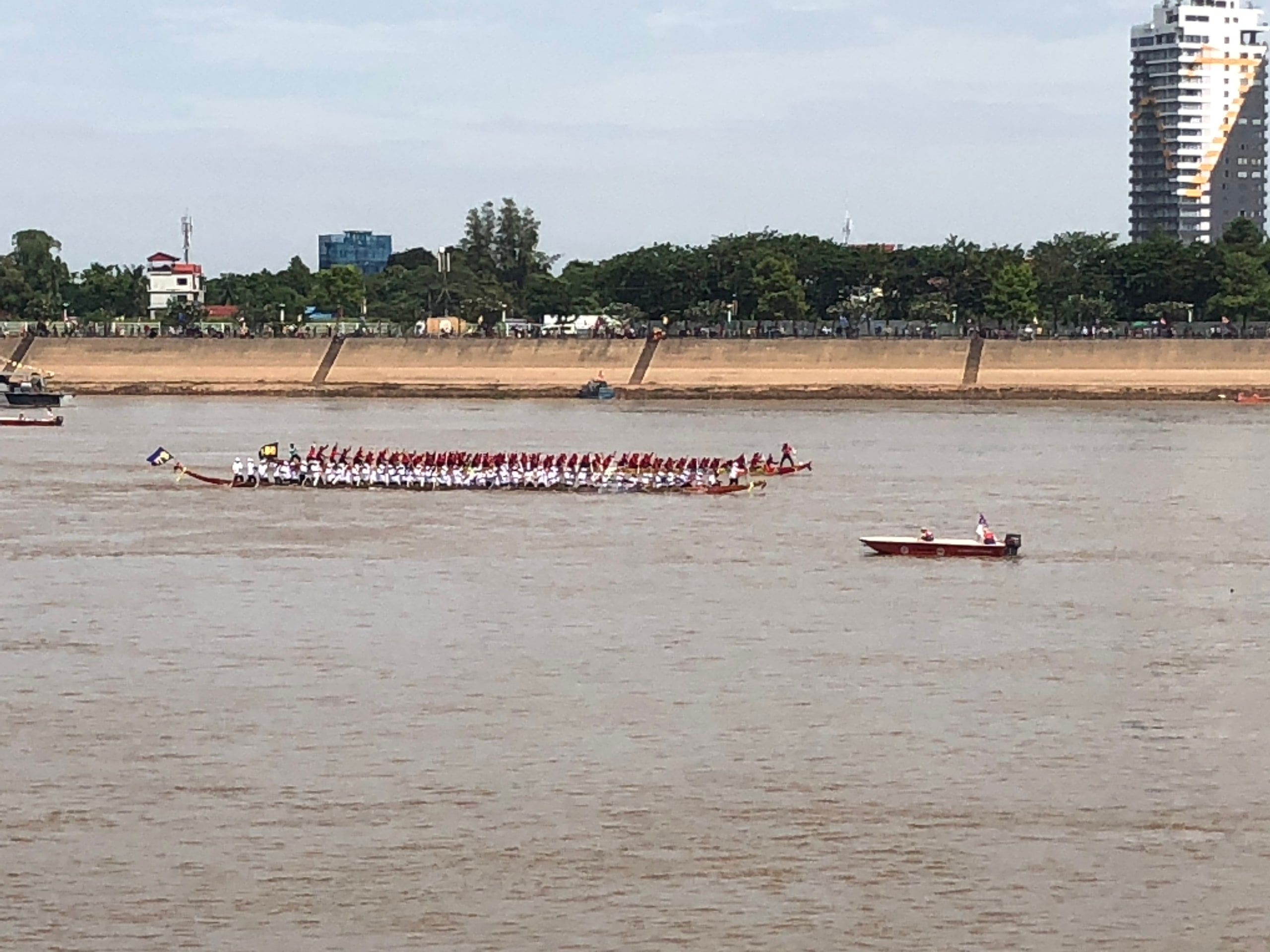 Une longue pirogue de course et ses rameurs sur le Tonlé Sap, devant les immeubles de la presqu'île de Chroy Changvar