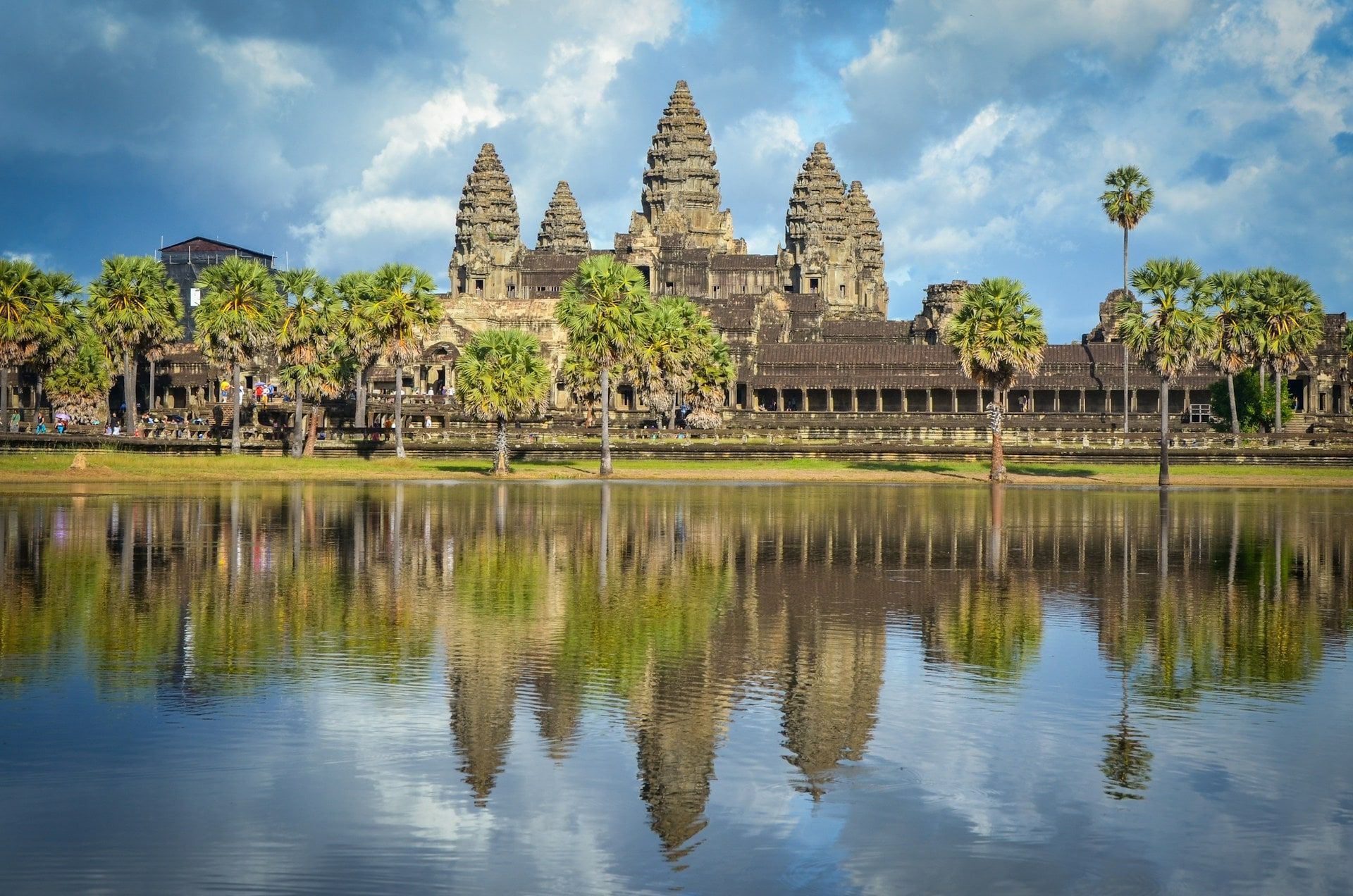Angkor Wat's towers and sugar palms reflected in the pond under a heavy sky