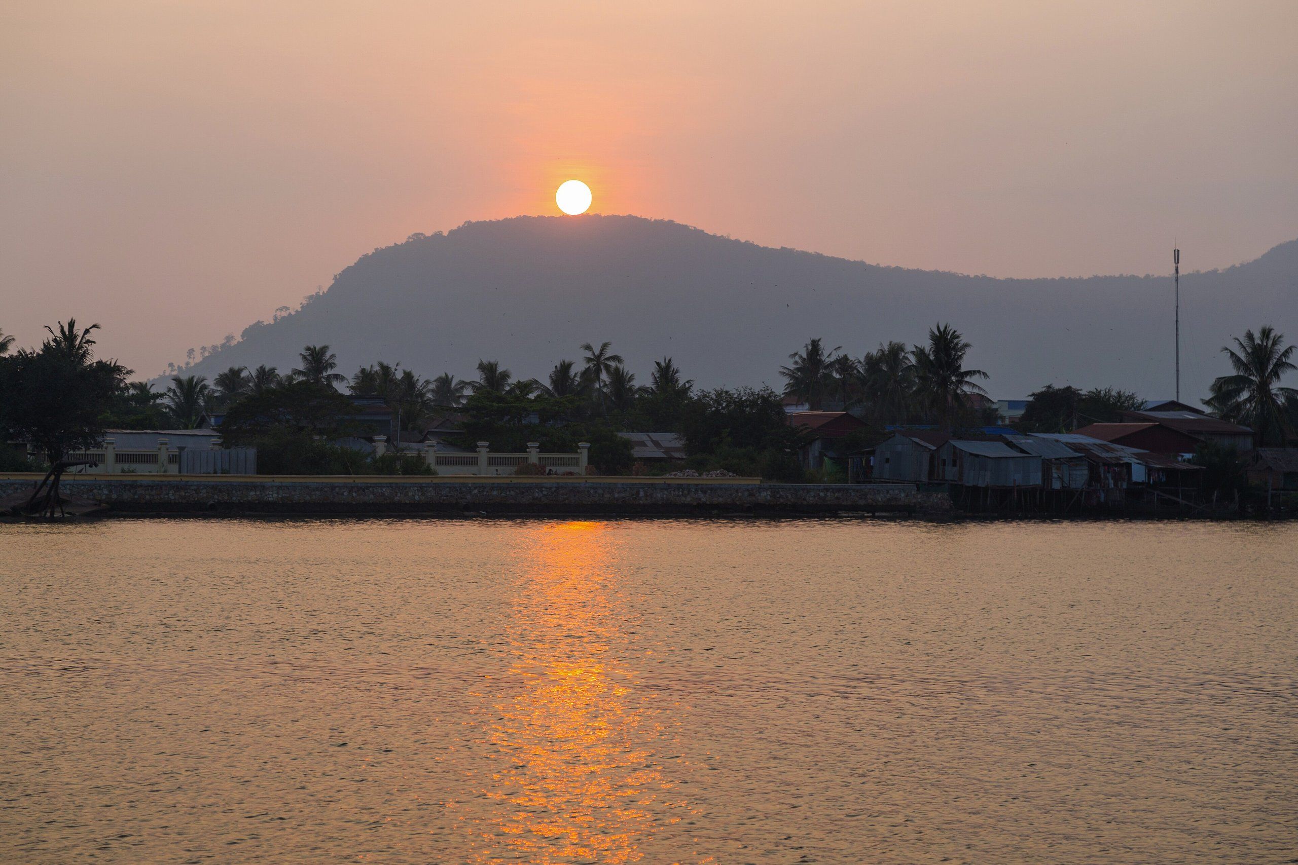 Le soleil se couche sur la Praek Tuek Chhu à Kampot, le massif de Bokor derrière