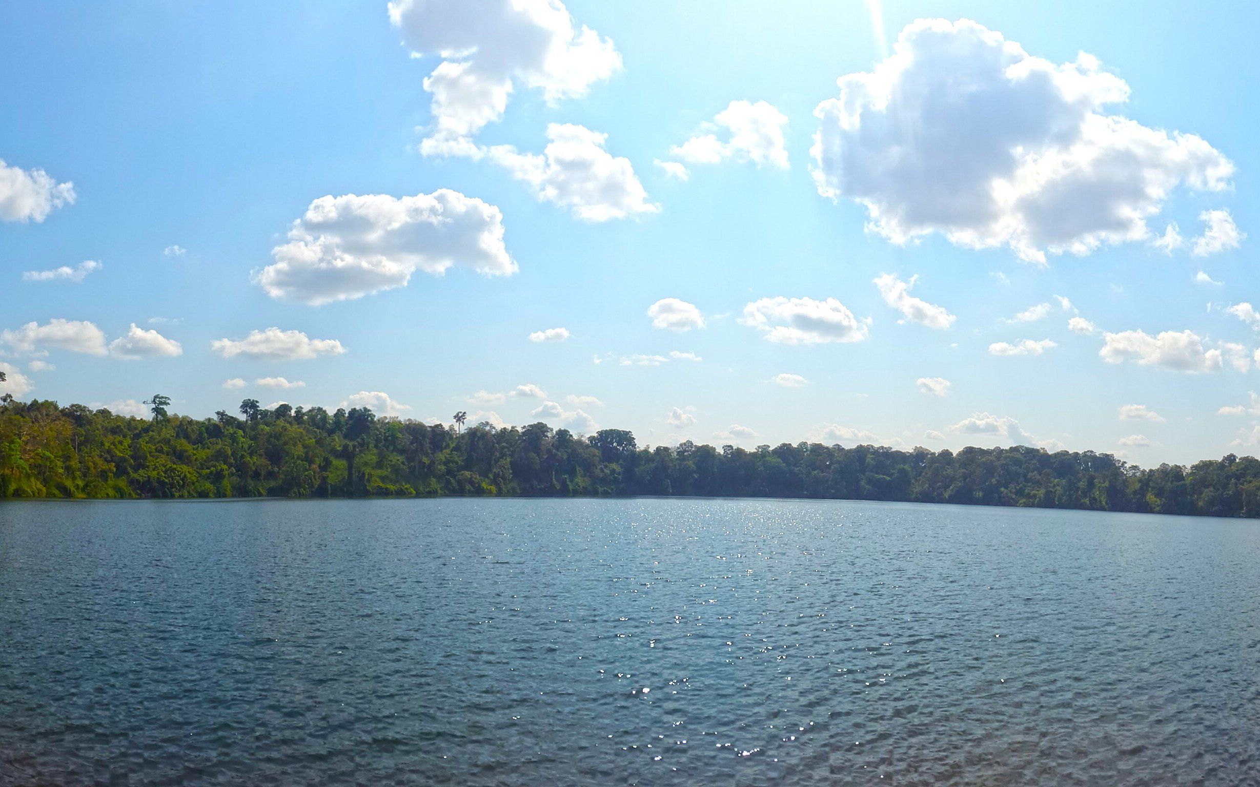 Le lac de cratère de Yeak Laom, bordé de forêt, sous un ciel nuageux
