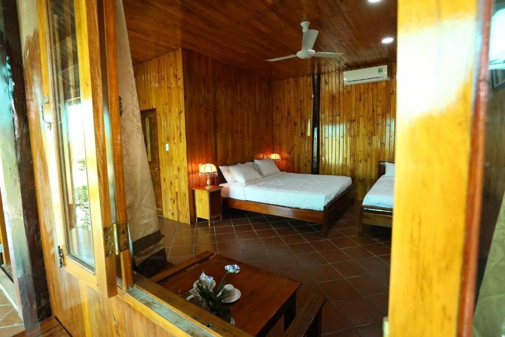 A room at Boutique Lodge Can Tho, with wood-paneled walls and ceiling, a double bed and an open French door