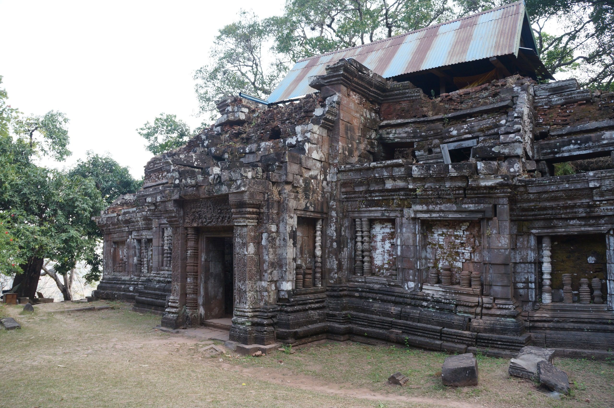 A ruined sandstone pavilion at Vat Phou, under a protective metal roof