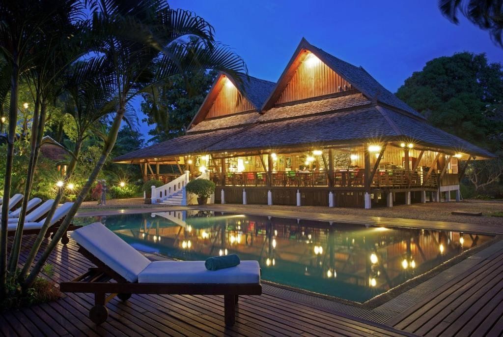 The lit pool at La Folie Lodge at night, in front of the restaurant's wooden pavilion