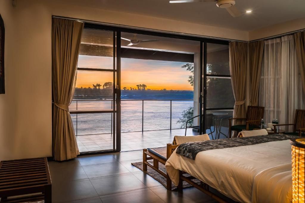 A room at The River Resort, its glass doors open onto the Mekong at sunset