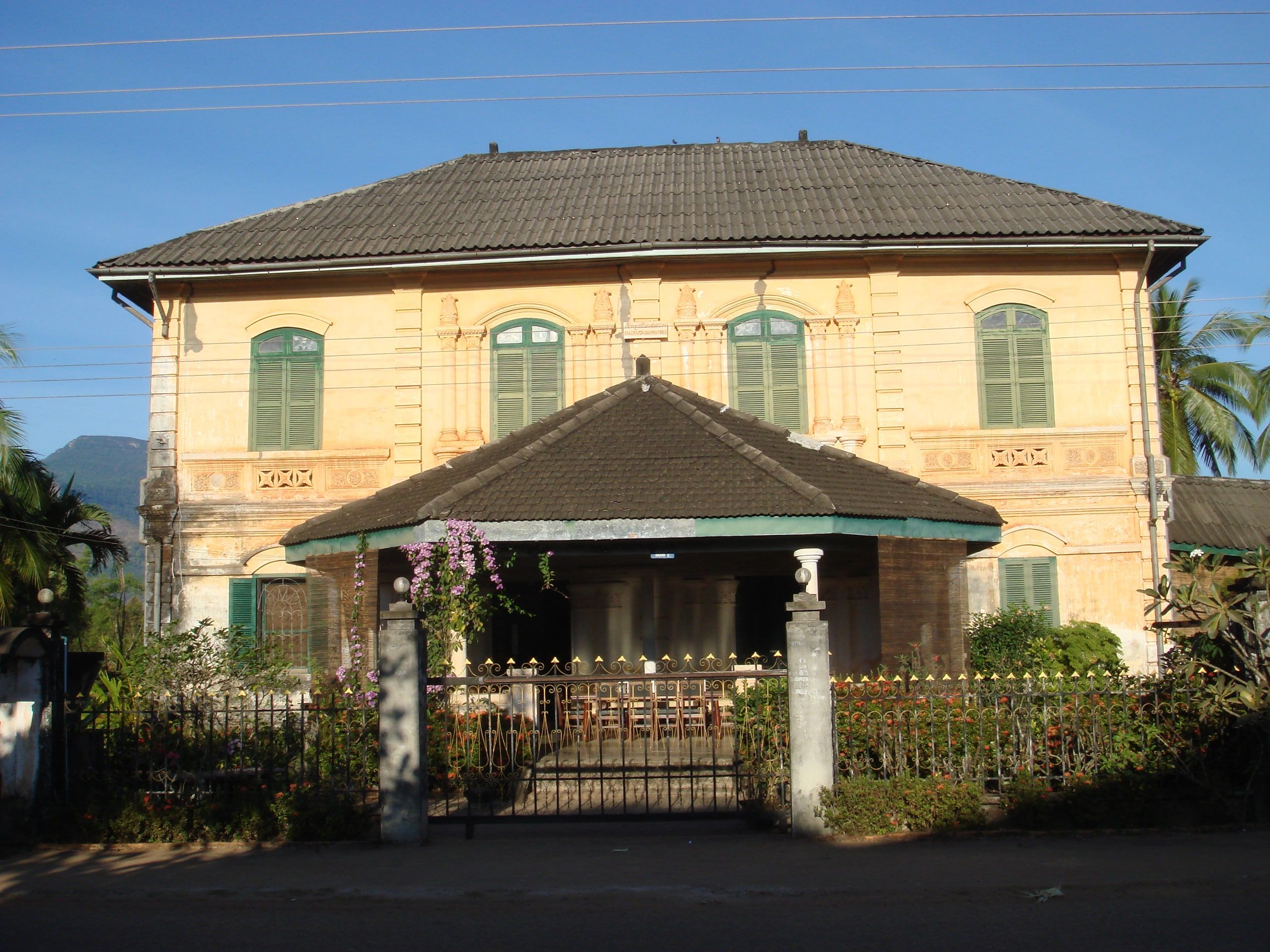 The former royal residence in Champasak, a yellow colonial house with green shutters