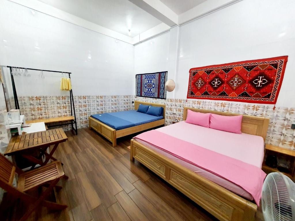 Une chambre du Homestay Khoa, deux lits et des tapis rouges et bleus au mur
