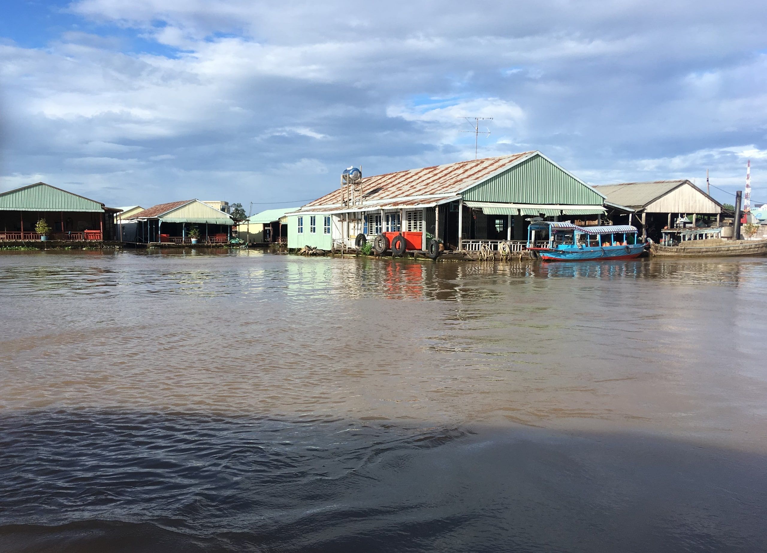 Des maisons flottantes sur le Bassac à Châu Đốc, un bateau bleu amarré devant