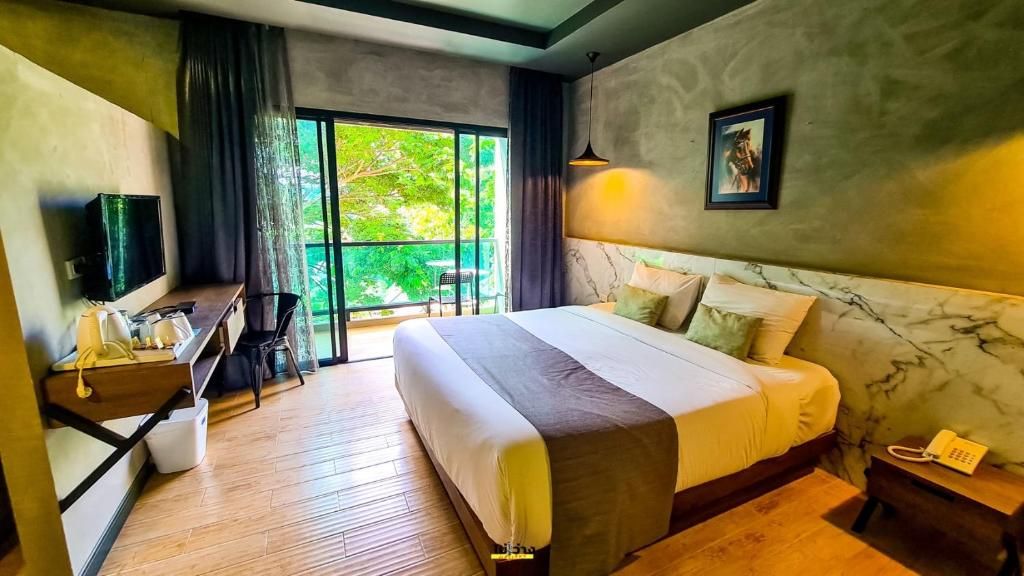 A room at the Teak Garden, grey walls and a white bed, glass doors open onto a balcony and trees