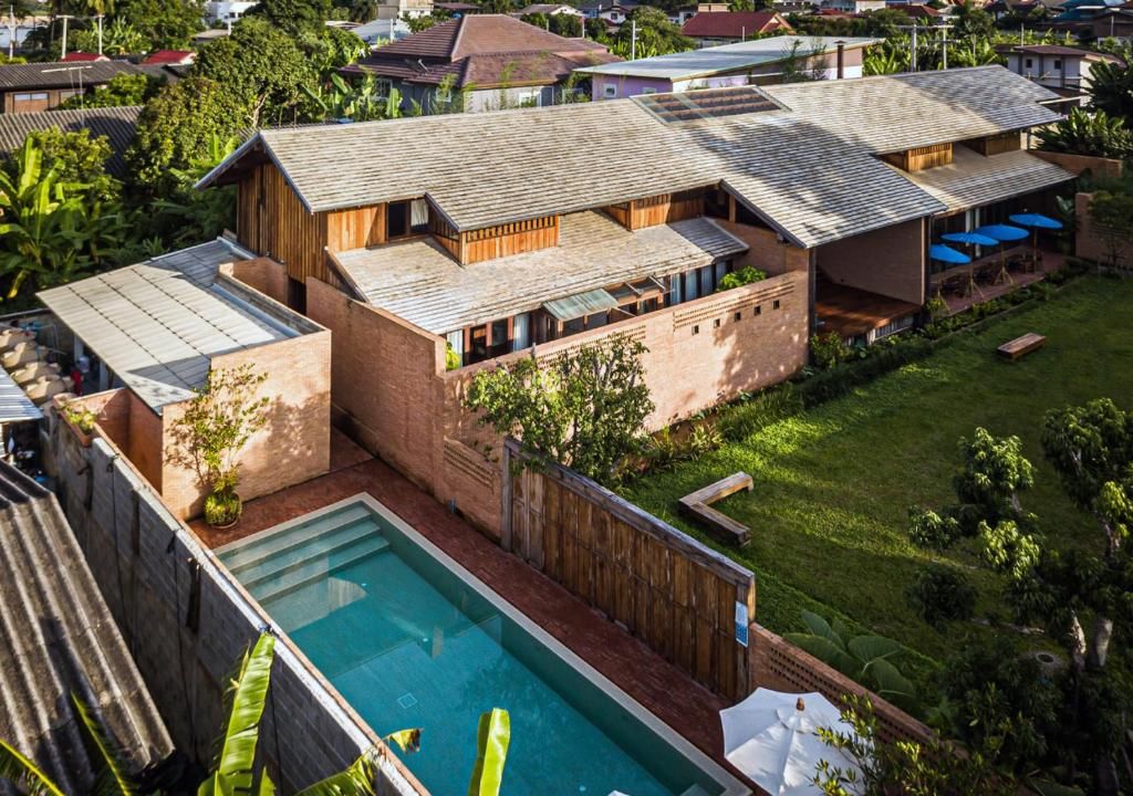 L'Athita vu d'en haut : des bâtiments de brique et de bois, une piscine étroite et une pelouse plantée d'arbres