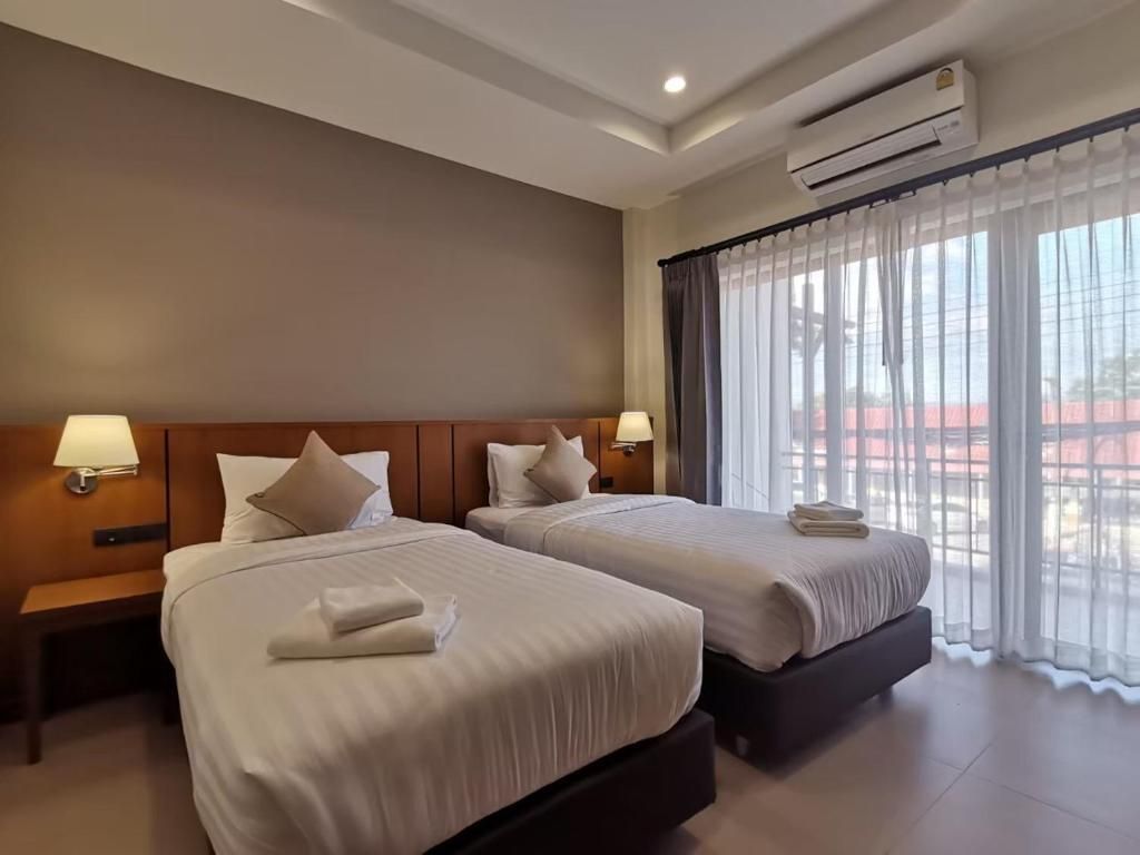Une chambre à deux lits du Pak Ping Rim Khong, baie vitrée voilée de rideaux blancs