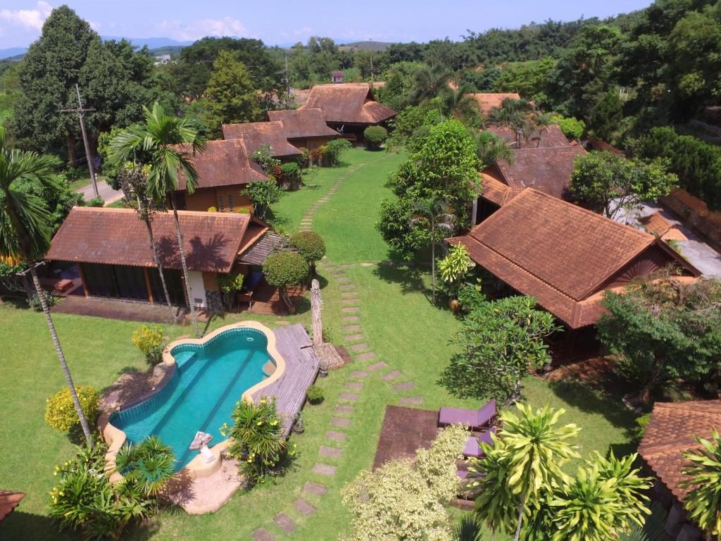 Les bungalows à toits de tuiles du Viang Yonok dans un jardin, autour d'une piscine aux contours arrondis