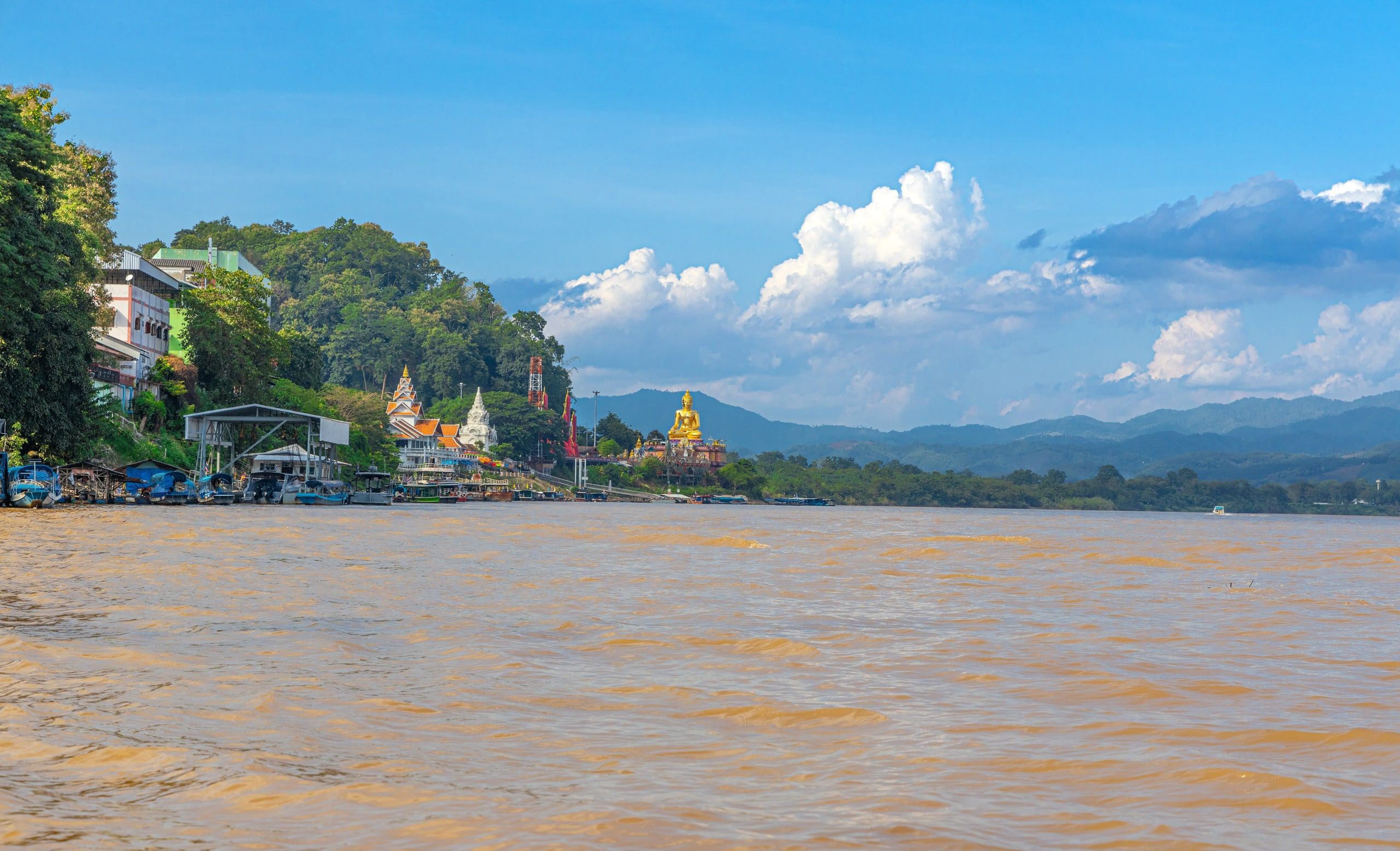 Le Mékong brun au Triangle d'or, le Bouddha doré au loin sur la rive thaïlandaise