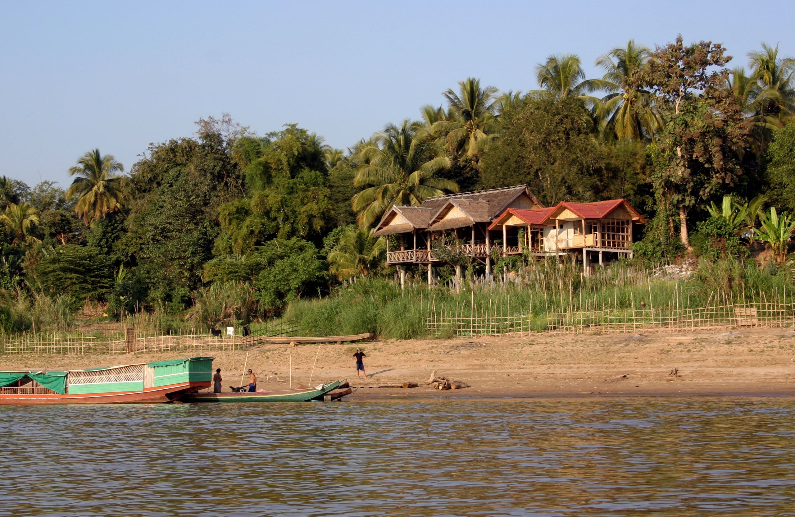 Stilt houses under palm trees on the Huay Xai bank