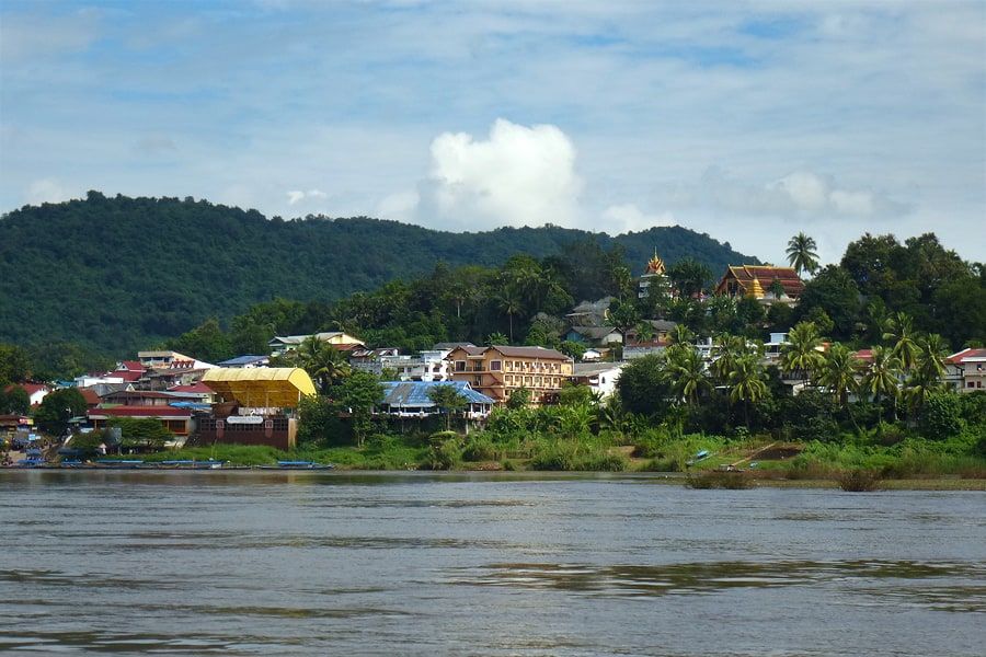 Huay Xai seen from the river, houses below the hills and a temple on the height