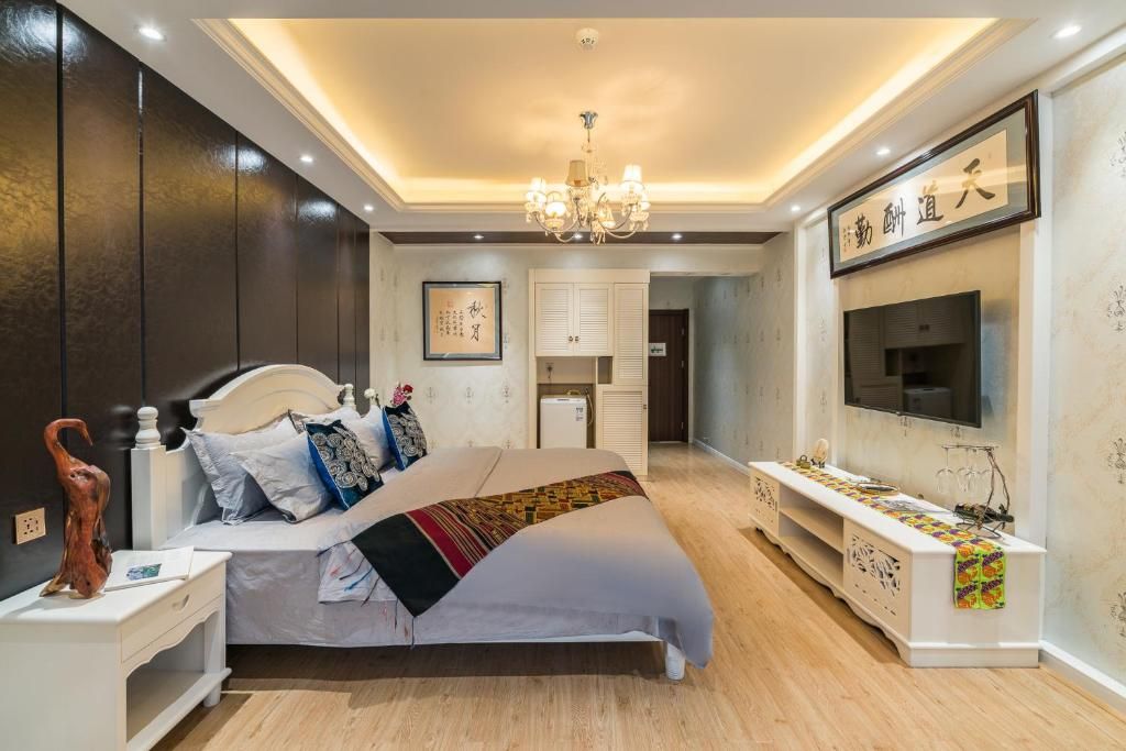 A room at Doudou Meilan Fengqing Inn, a large bed with a woven throw, a chandelier and calligraphy on the wall