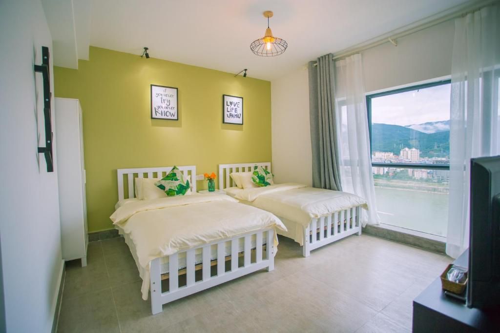 A room with two white beds at Mekong At Home, a large window over the Mekong and the mountains