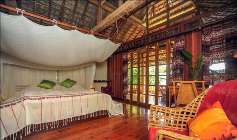 A wooden room at You Ran Tai, a bed under a stretched mosquito net, a high roof and glass doors