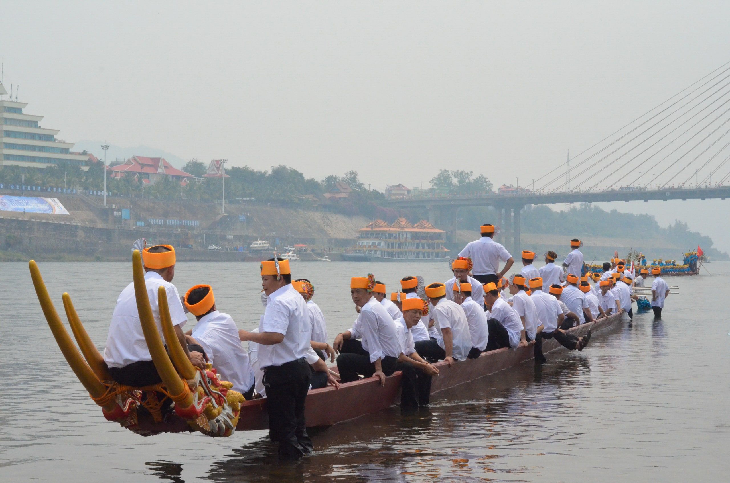 Rowers in white and orange on a long boat during the Water-Splashing Festival