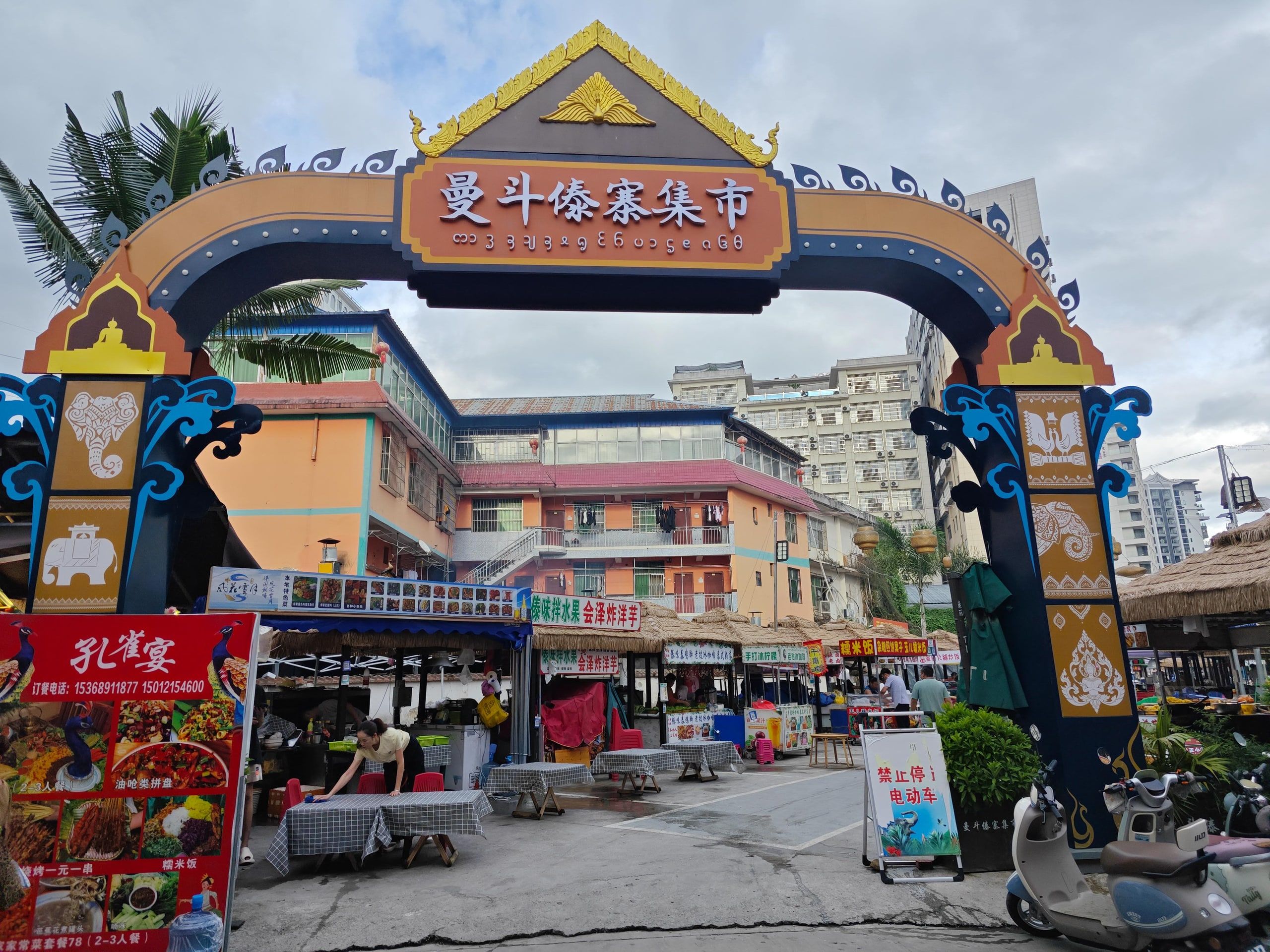The carved gateway of a Jinghong market and its street stalls