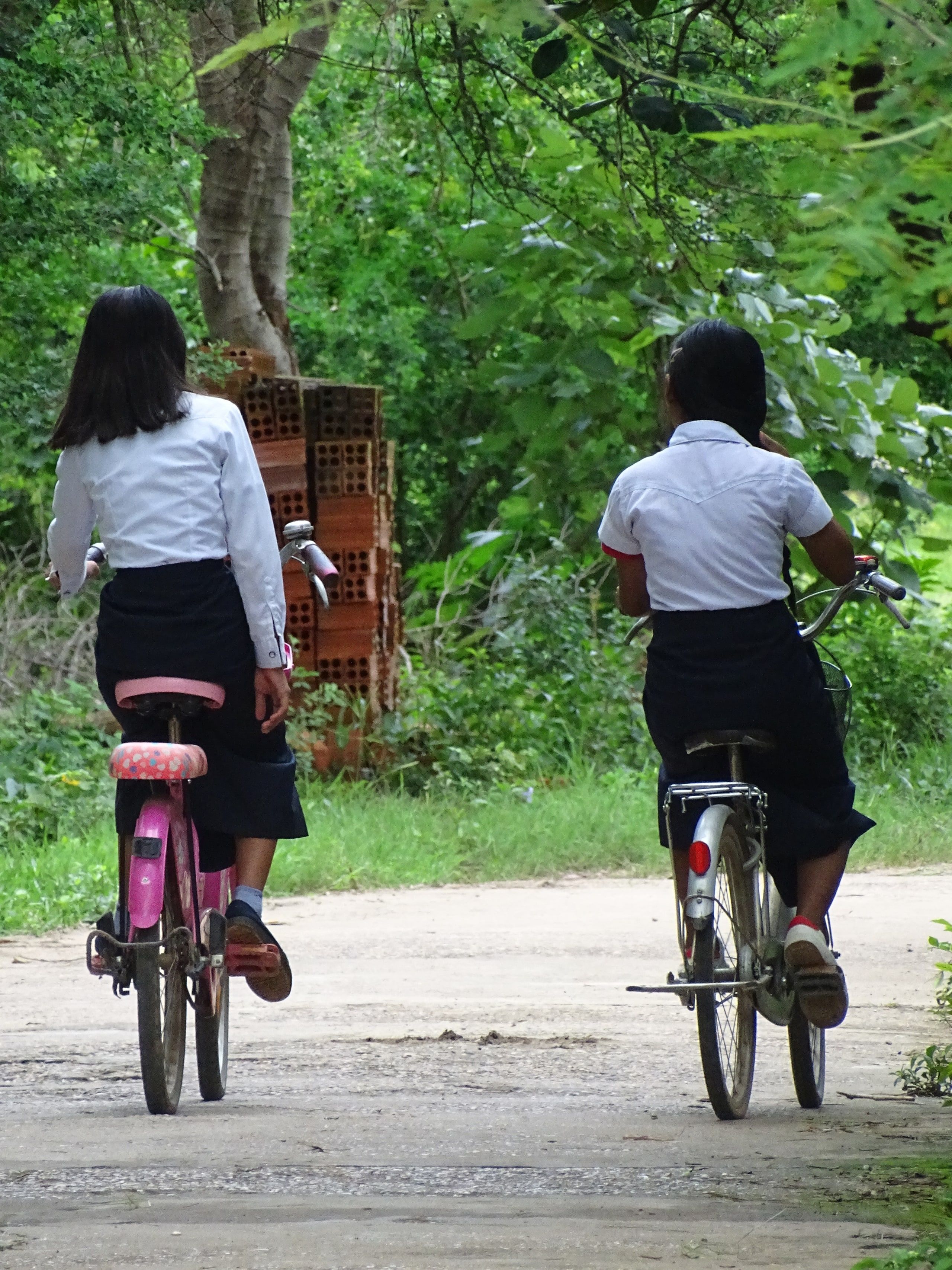 Two schoolgirls cycling on a path on Koh Trong