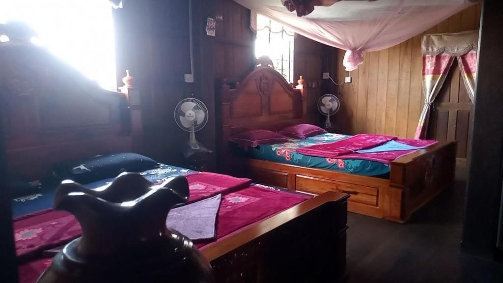 A wooden room at Tonle Mekong Homestay, two beds with pink sheets
