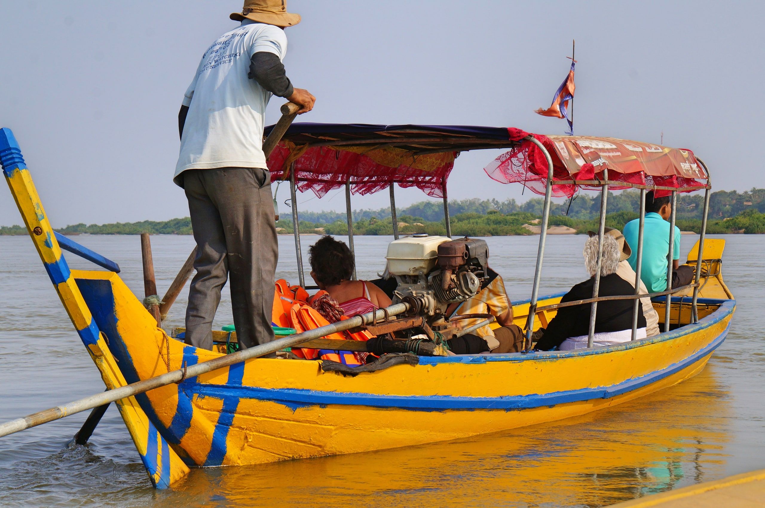 A tourist boat and its boatman at the Kampi dolphin pool