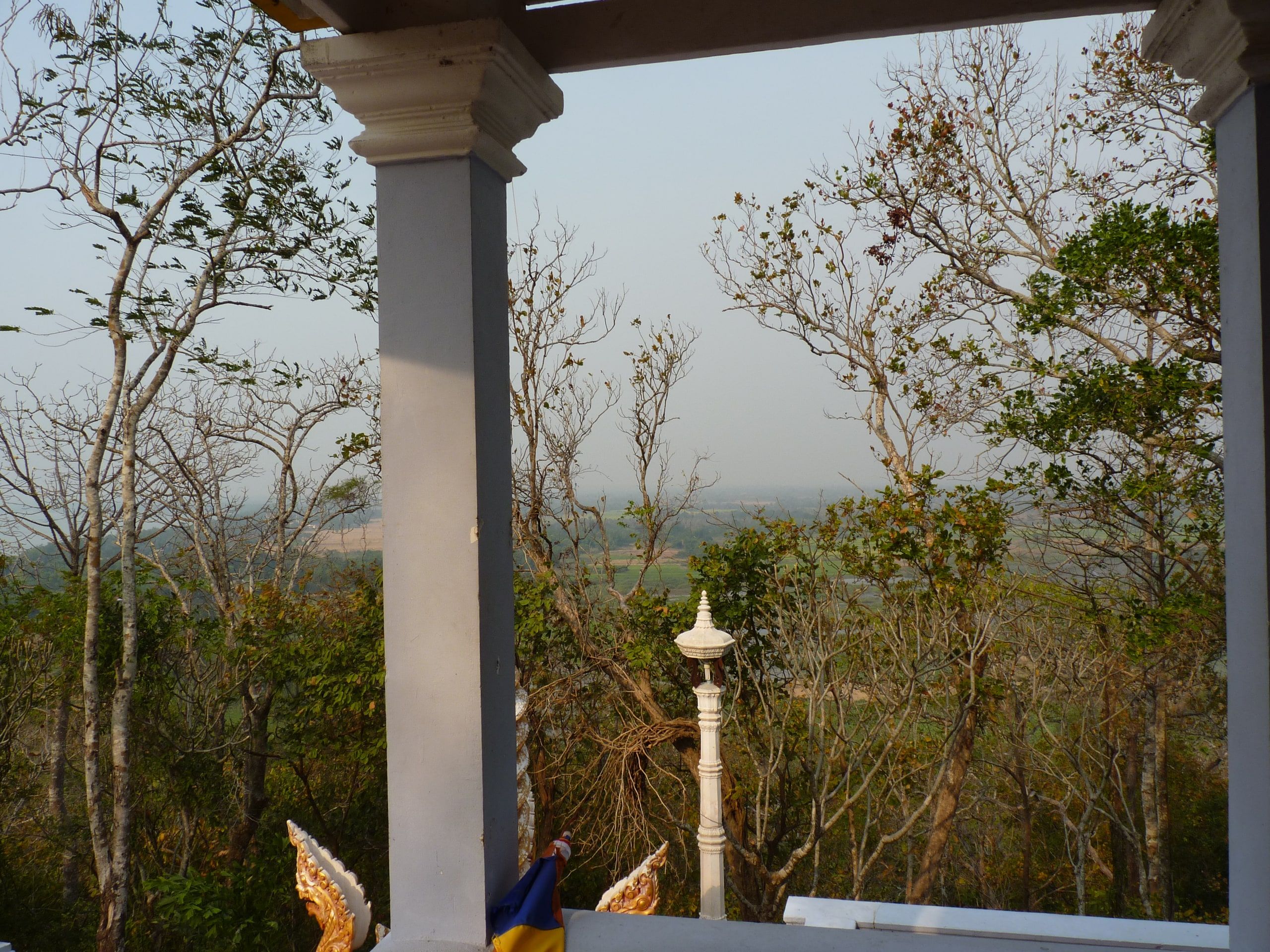 The view from Phnom Sambok hill, between dry trees and a pagoda pillar