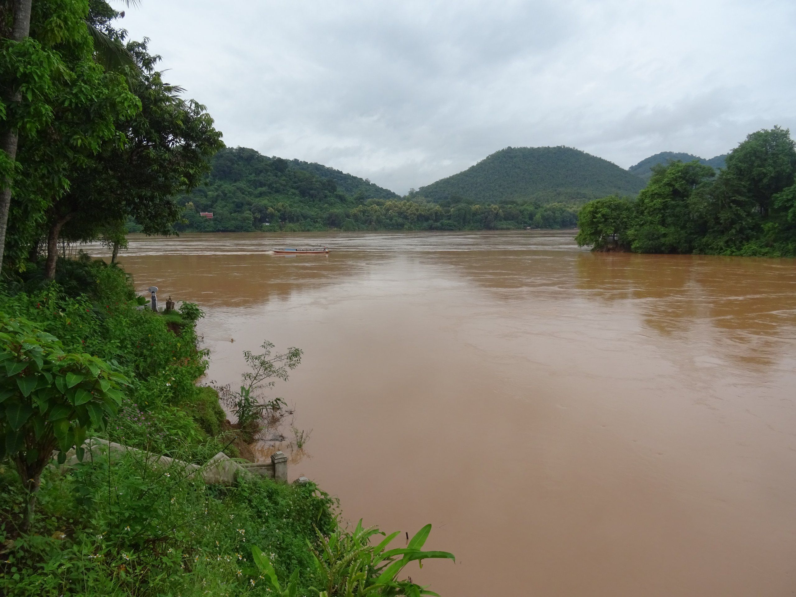 The swollen, brown Mekong at its confluence with the Nam Khan in Luang Prabang, below green hills