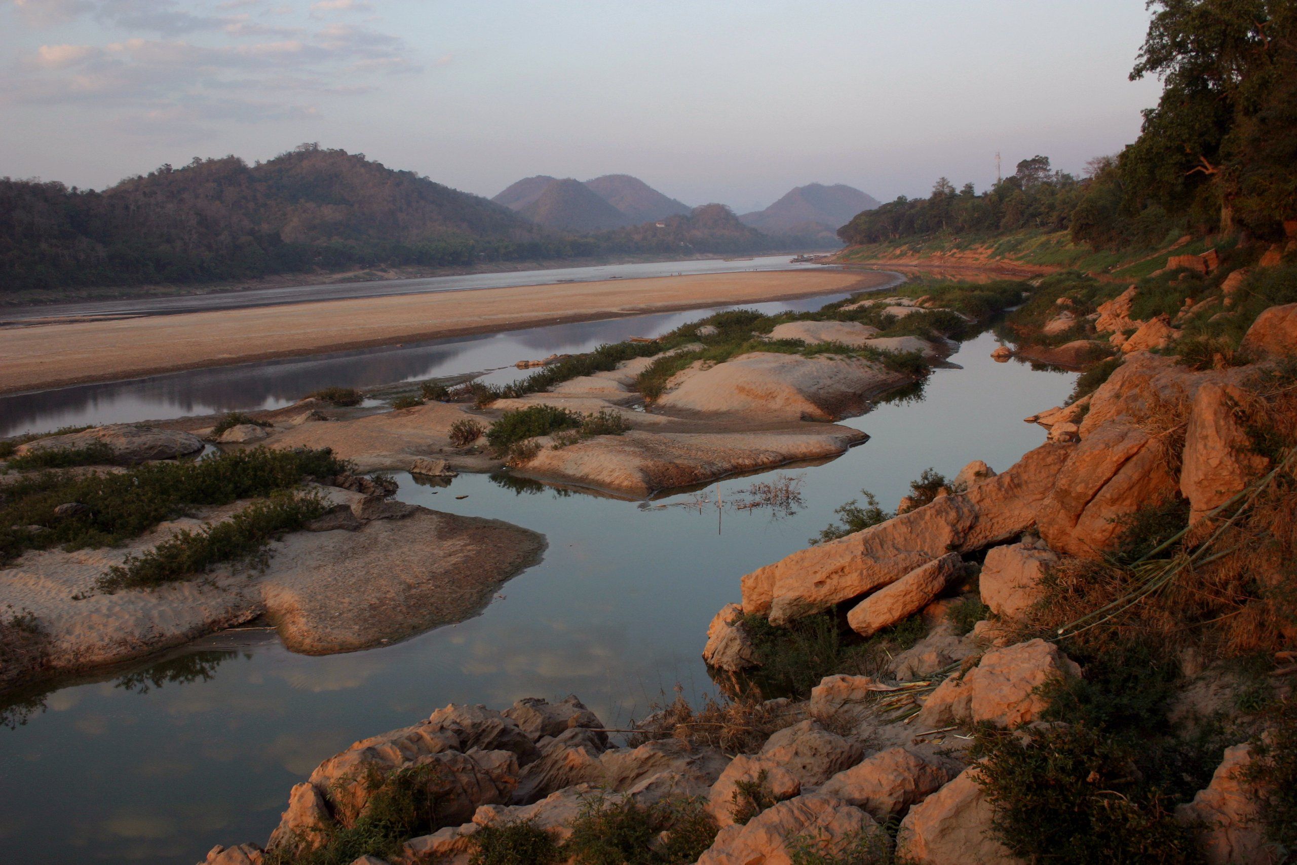 The Mekong at low water in Luang Prabang, between sandbanks and exposed rocks, at sunset
