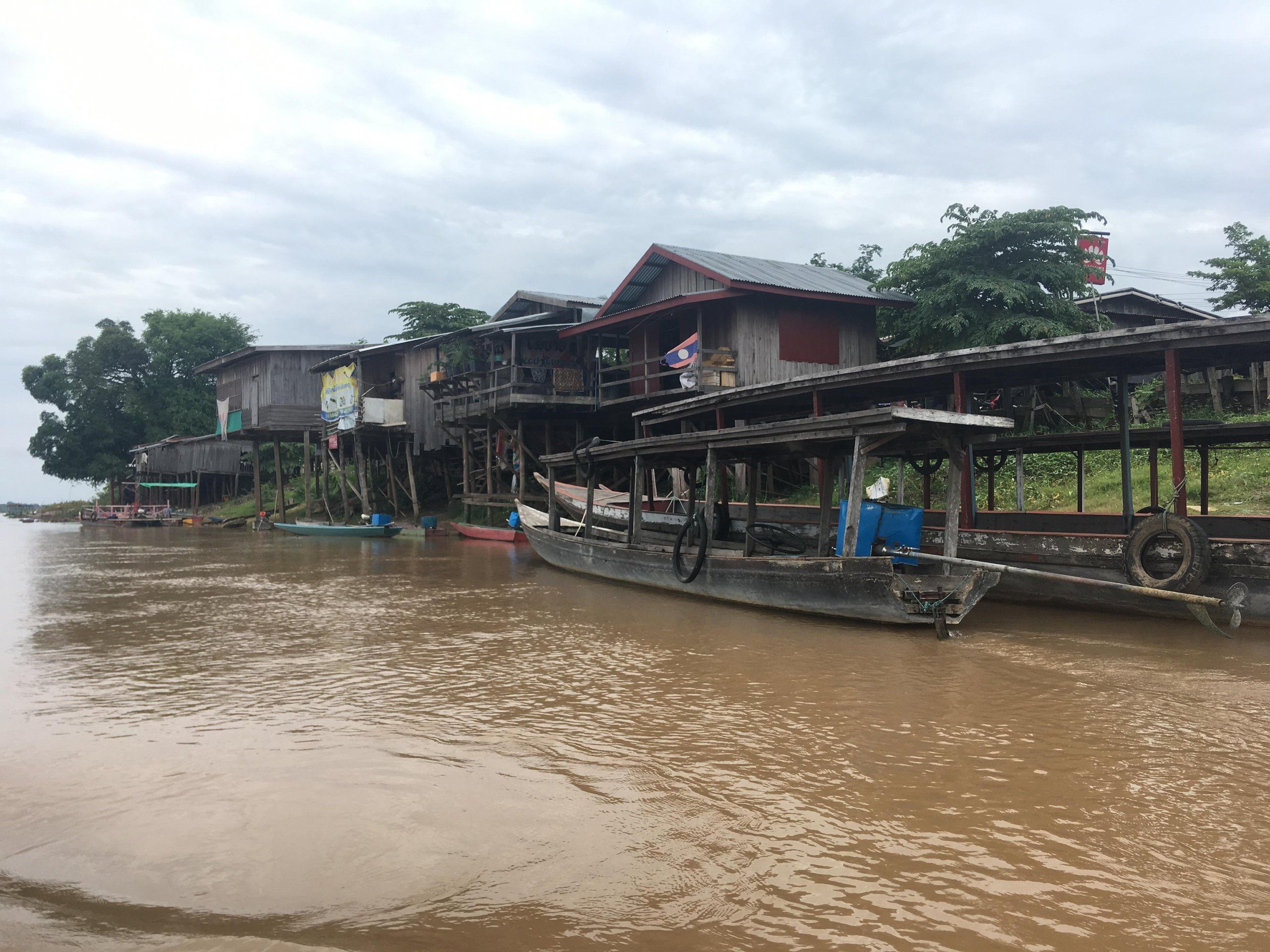 Stilt houses and boats on the banks of the brown Mekong, in southern Laos