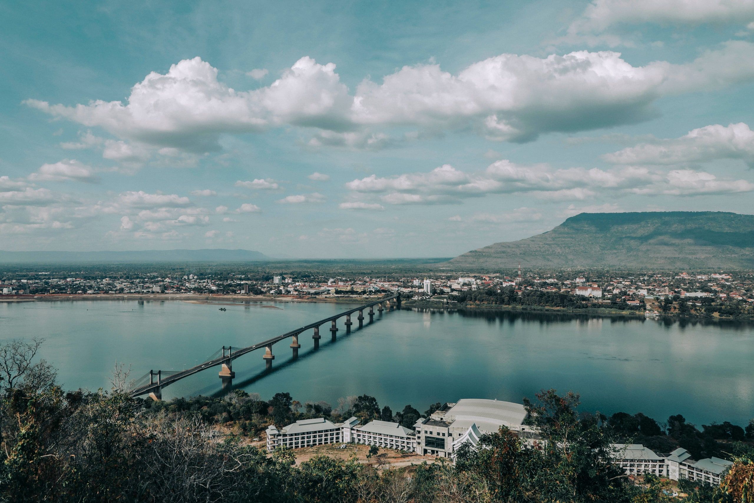 A bridge across the Mekong seen from above, under a cloudy sky