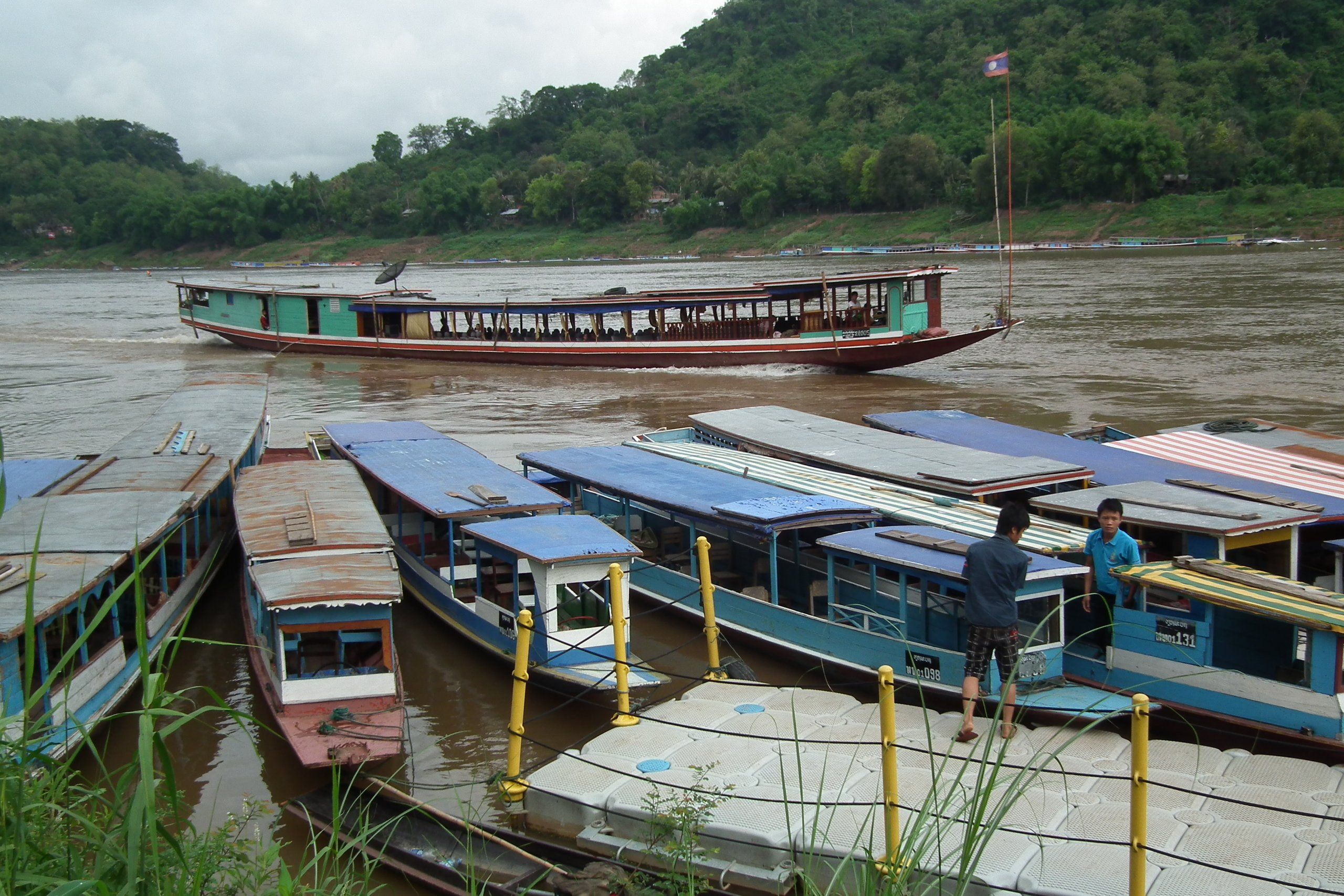 Slow boats moored on the Mekong at Luang Prabang, under a cloudy sky