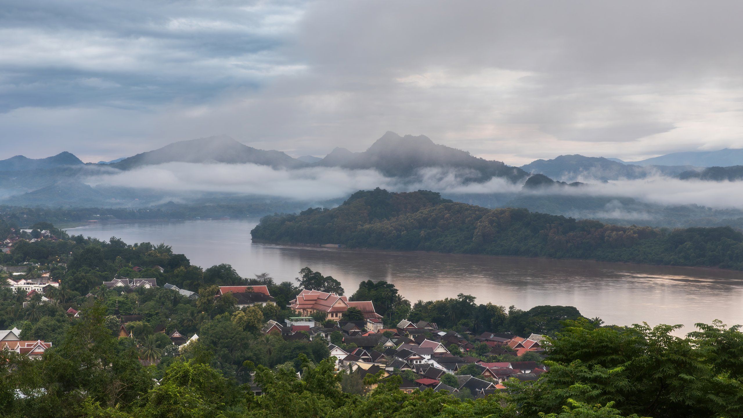 Luang Prabang at dawn from Mount Phousi: the muddy Mekong, rooftops and mountains in the mist