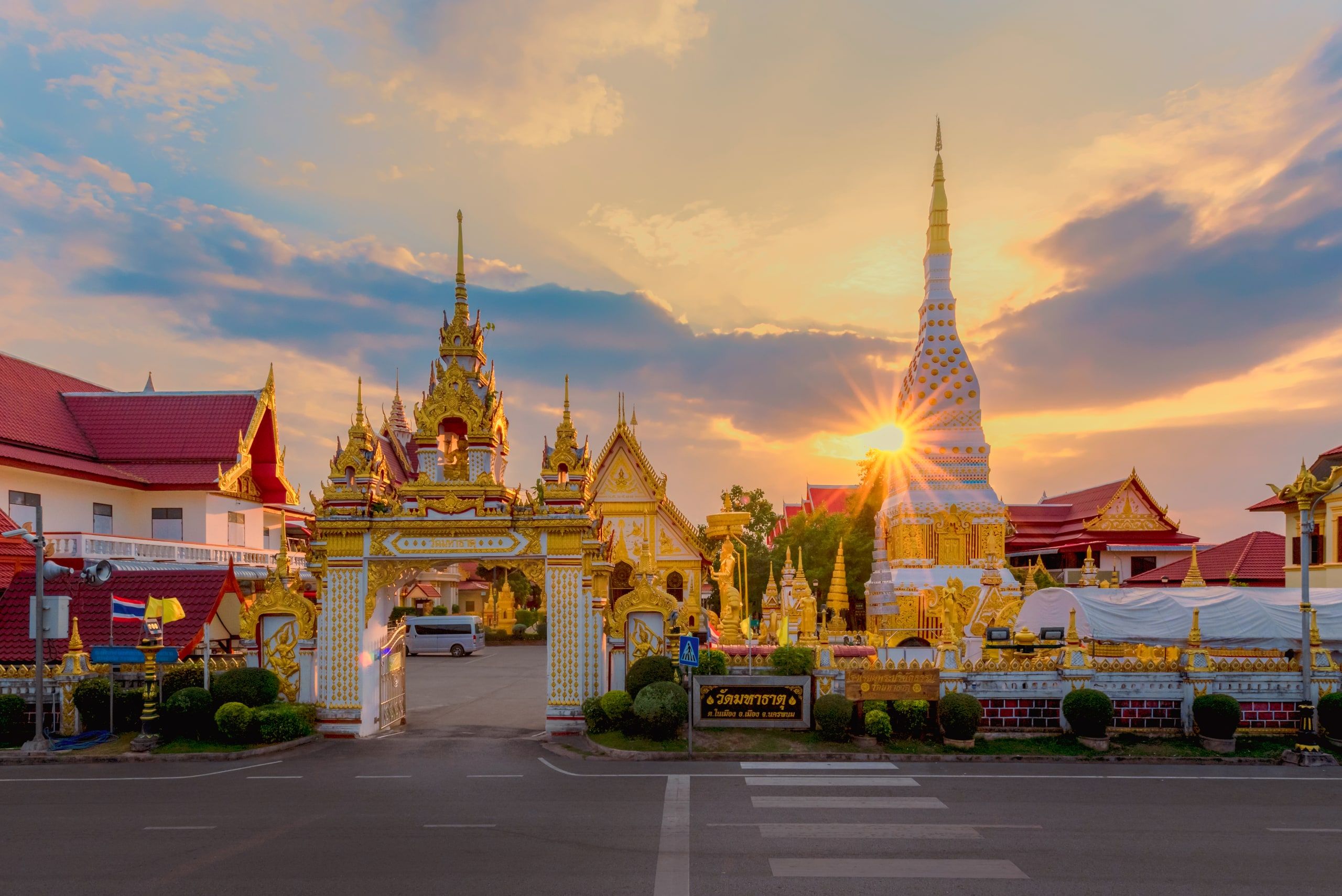 Le Wat Mahathat de Nakhon Phanom au coucher du soleil, sa porte dorée et son chedi blanc et or