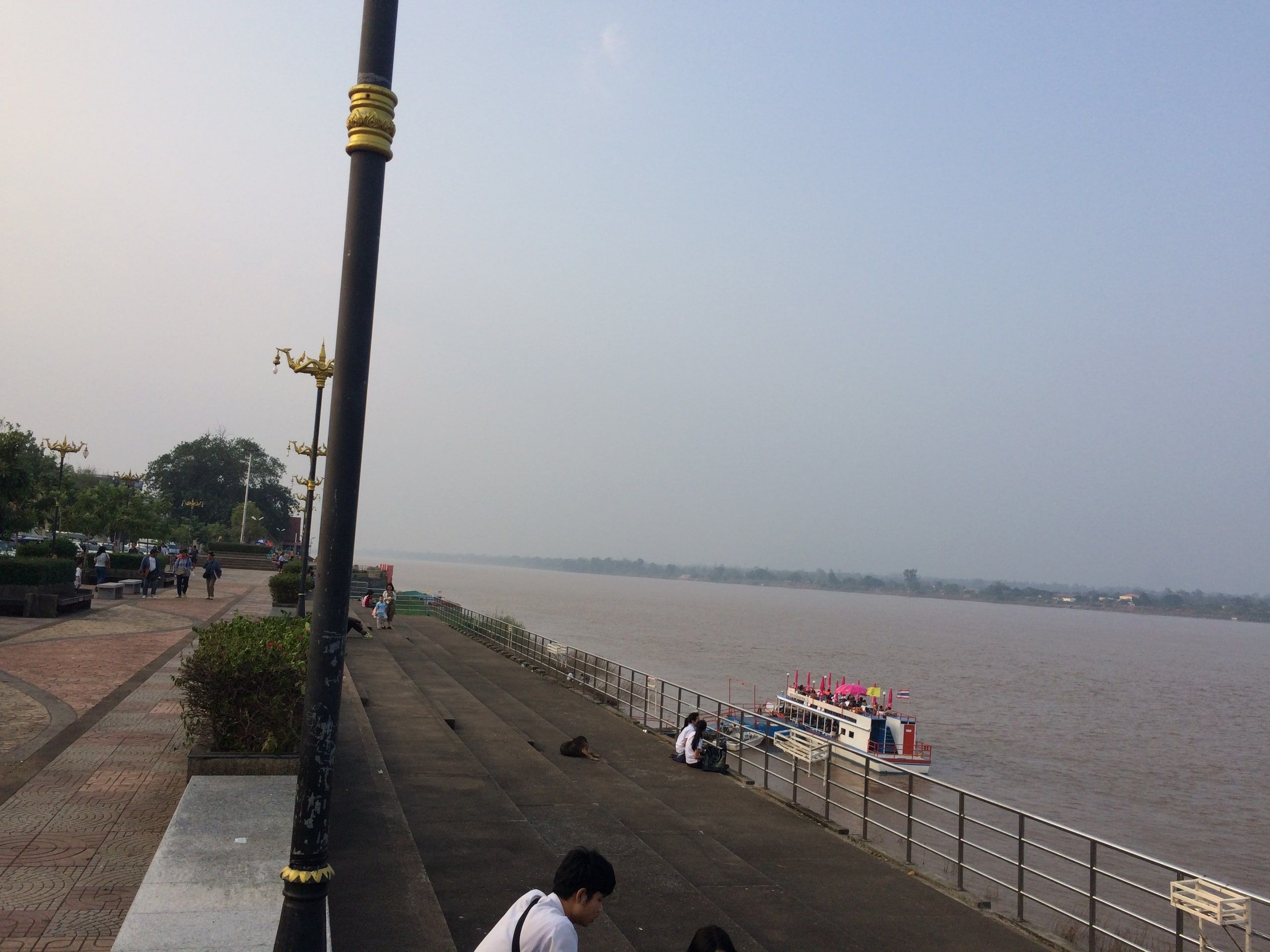 Le Mékong à Nakhon Phanom depuis le quai, un bateau sur l'eau et la rive lao au loin