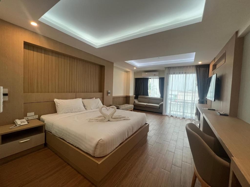 Une chambre du Square Hotel, un grand lit, un parquet clair et un coin salon devant la fenêtre