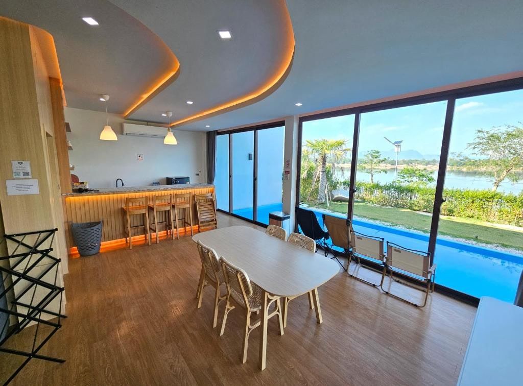 Une salle à manger lumineuse du Sunrise Resort, ouverte par une baie vitrée sur la piscine et un lac