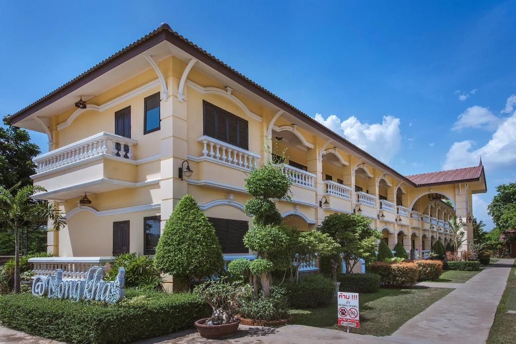 The yellow, white-balconied buildings of Park & Pool Resort behind clipped shrubs