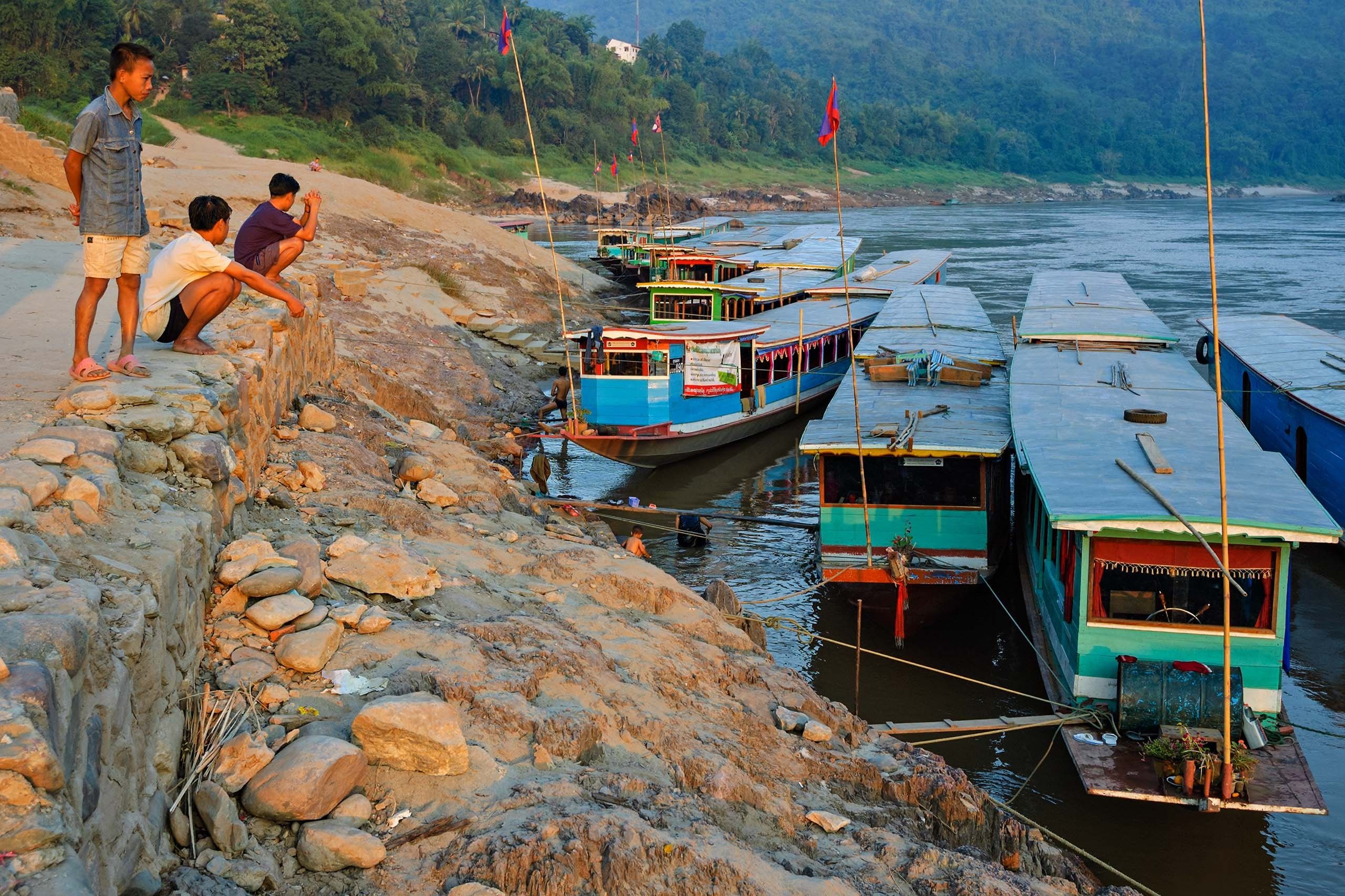 Slow boats moored along the rocky bank at Pakbeng at sunset