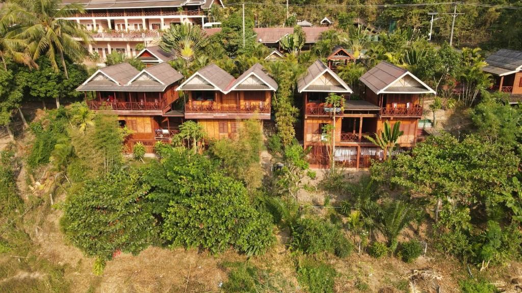 The wooden houses with balconies of Mekong Riverside Lodge, stepped up a leafy hillside