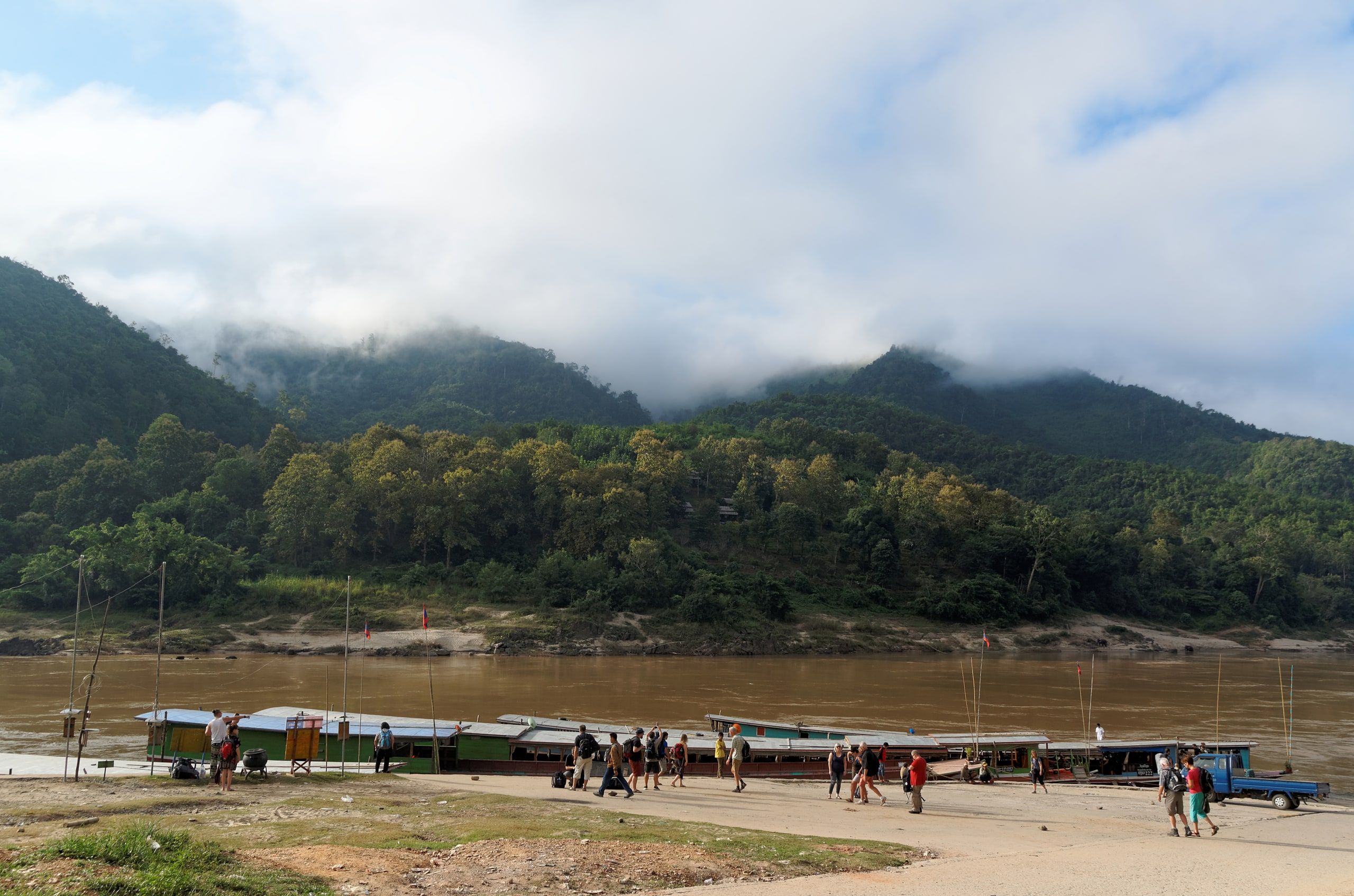 The sandy landing at Pakbeng, boats by the river and mountains in the clouds