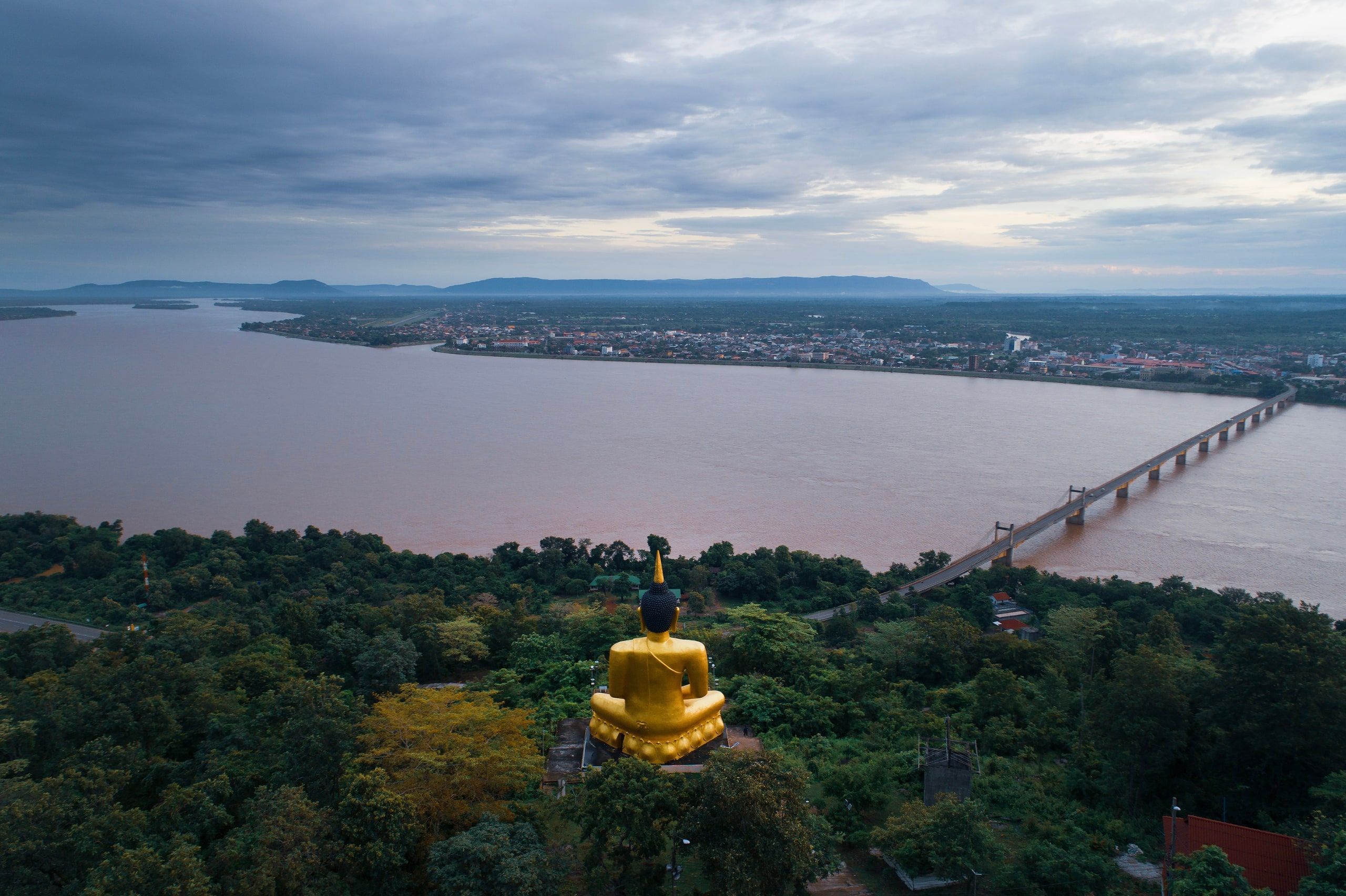 The golden Buddha of Phou Salao facing the Mekong, the Lao-Japanese bridge and Pakse