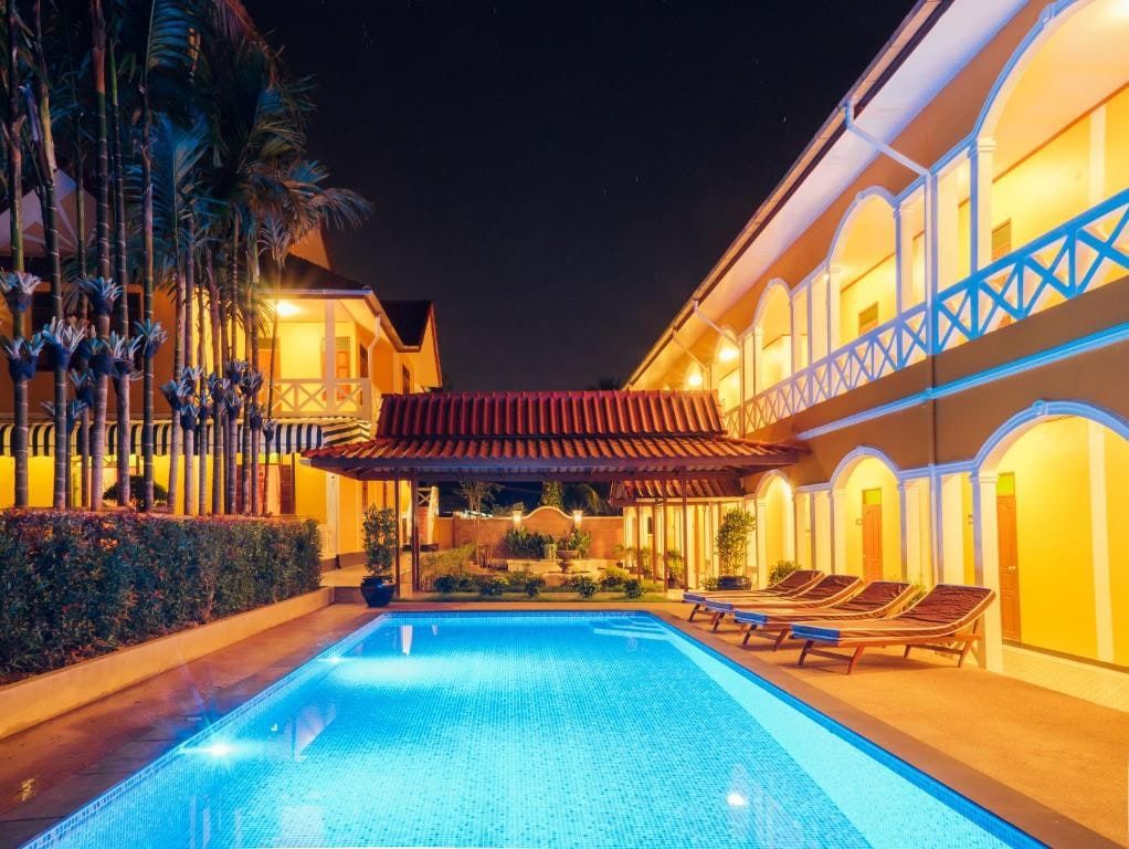 La piscine éclairée du Le Jardin Hotel, la nuit, entre les galeries à arcades