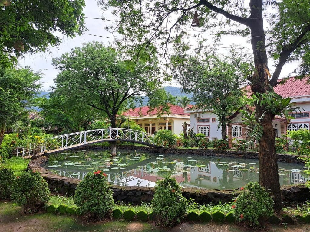 Le jardin du Xuanmai Garden Resort, un bassin et sa passerelle blanche sous les arbres