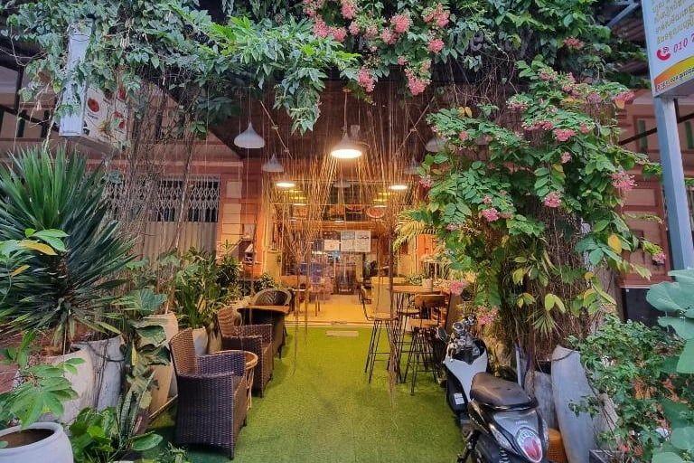 The entrance to Stay Sweet, rattan armchairs under a trellis of pink flowers