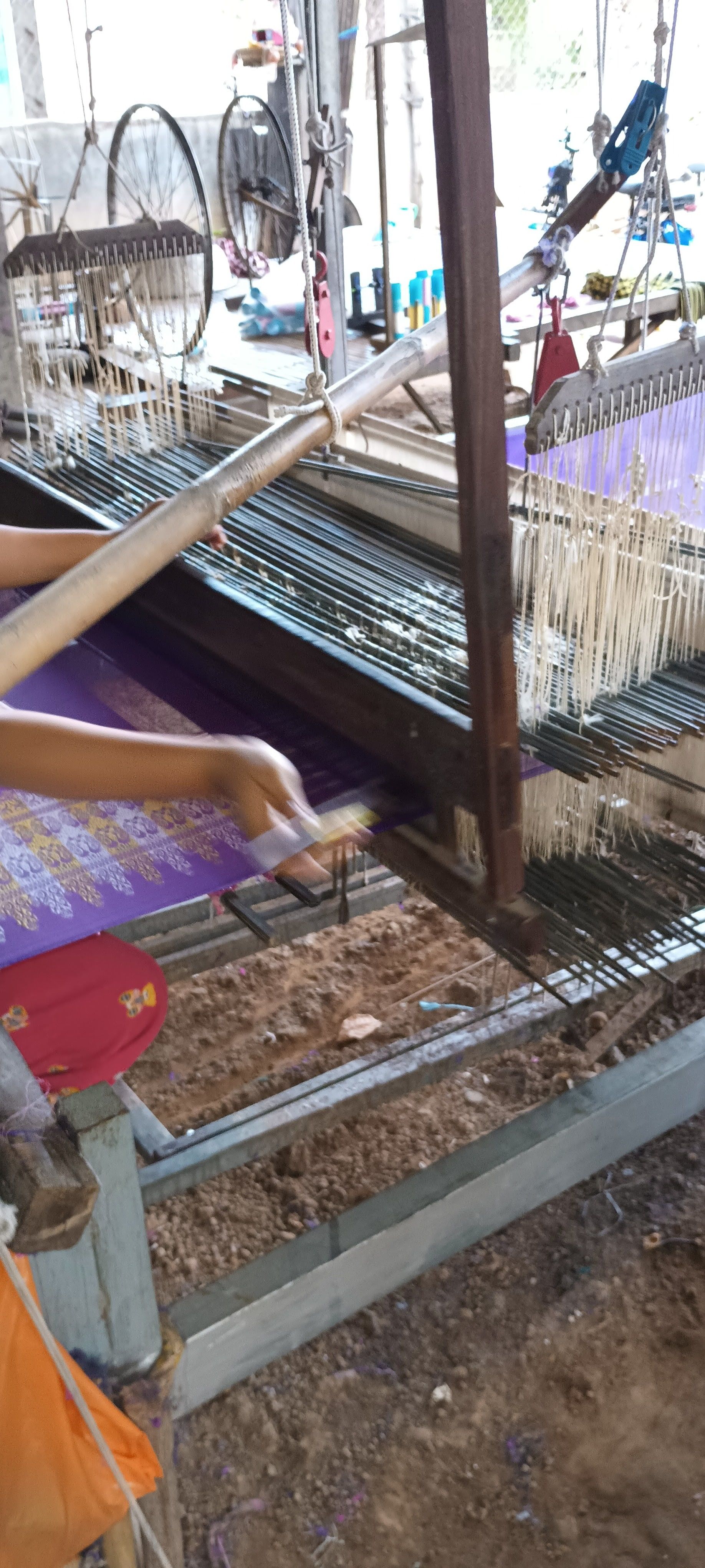 A hand weaving purple silk on a wooden loom on Koh Dach
