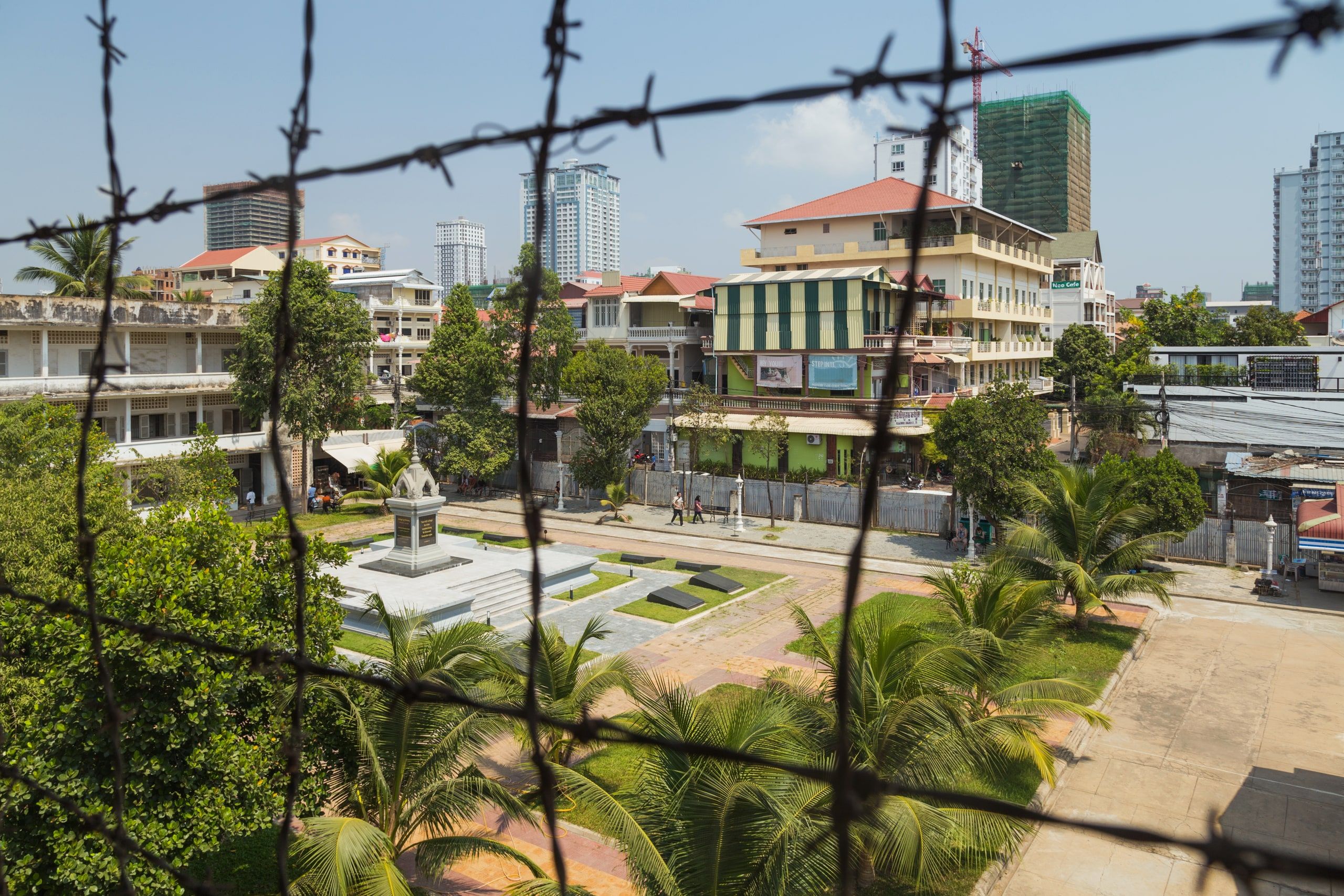 The Tuol Sleng courtyard seen through the barbed wire of a former prison walkway